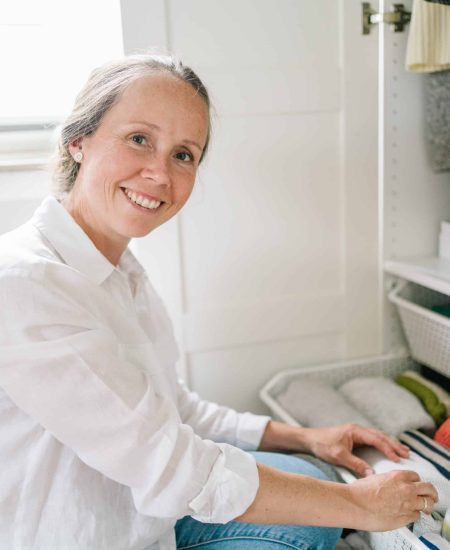 White haired woman sitting and organizing her drawer, looking at the camera