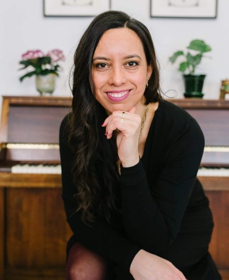 A black dressed woman looking at the camera, with one of her hands under her chin