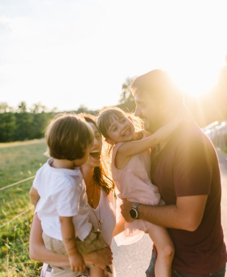 a family of four embracing each other during the sunset